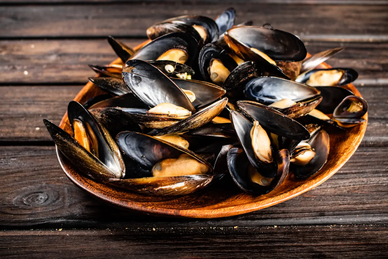 Mejillones frescos en una fuente de madera, ideales para recetas de mariscos y platos gourmet.