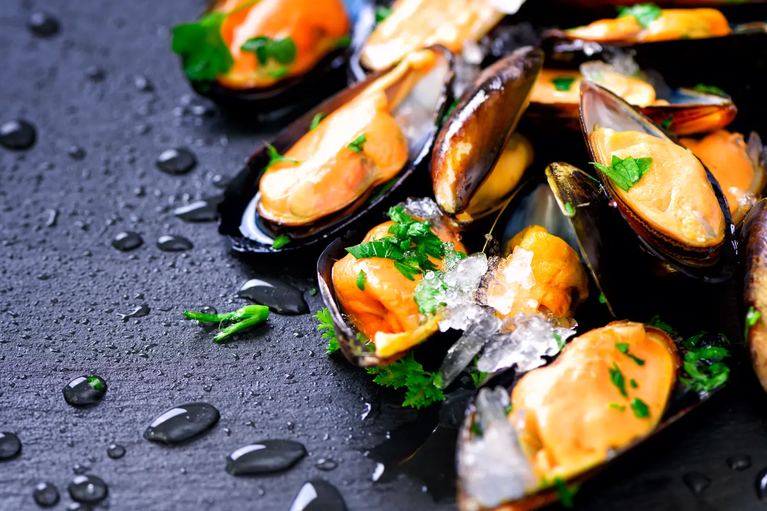 Mejillones frescos sobre una superficie oscura, decorados con hierbas verdes y hielo picado, con gotas de agua que resaltan su frescura. Ideal para platos de mariscos.
